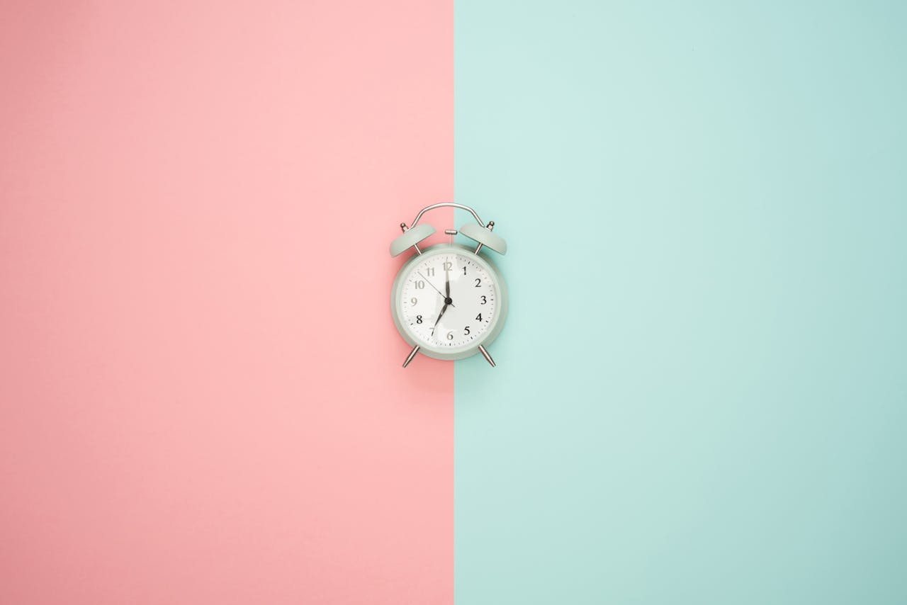 services-01 A vintage round clock on a split pastel pink and blue background.