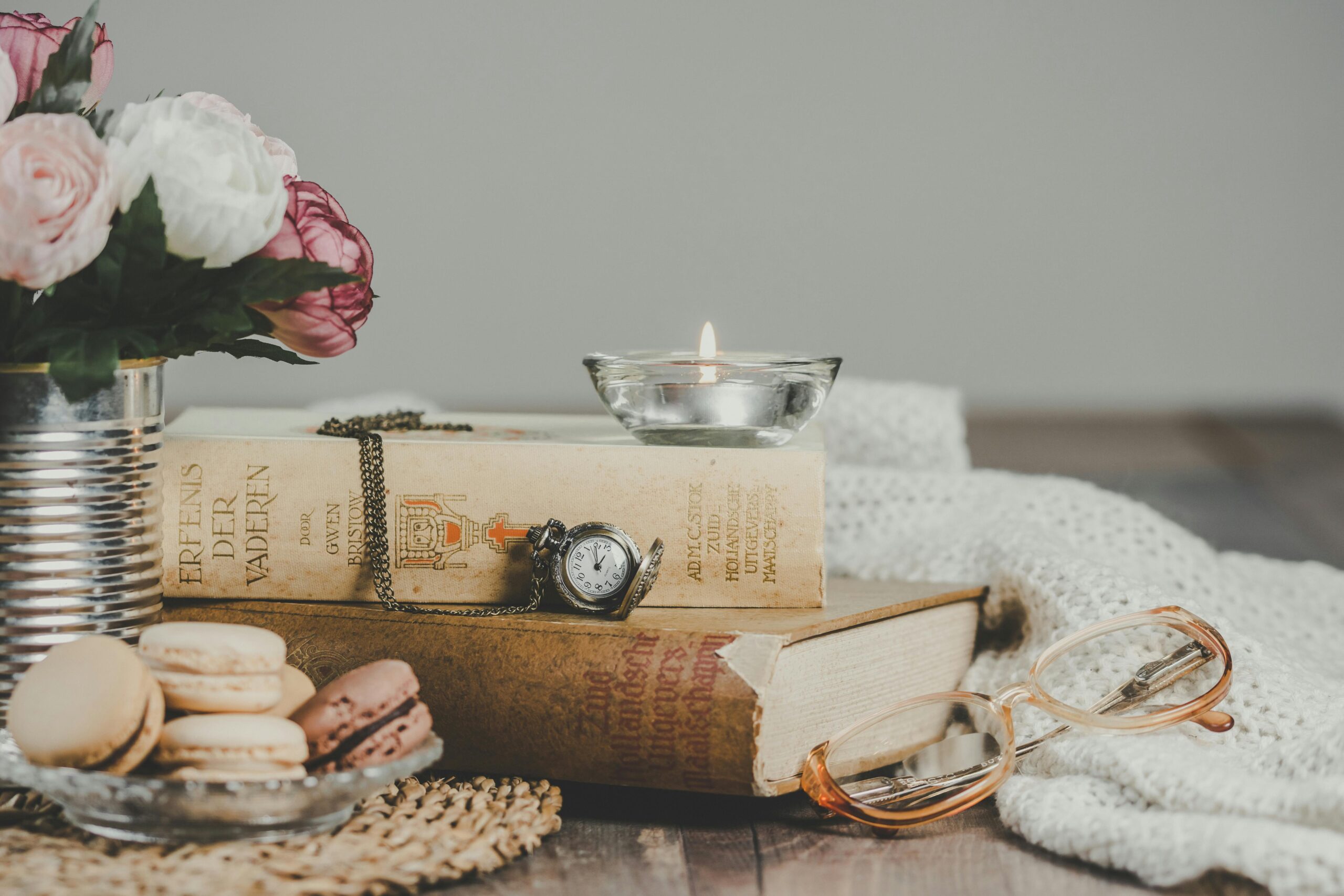 Kuidas vabaneda teiste ootustest ja jääda endaks Vintage still life with books, macarons, candle, and flowers on a cozy table.