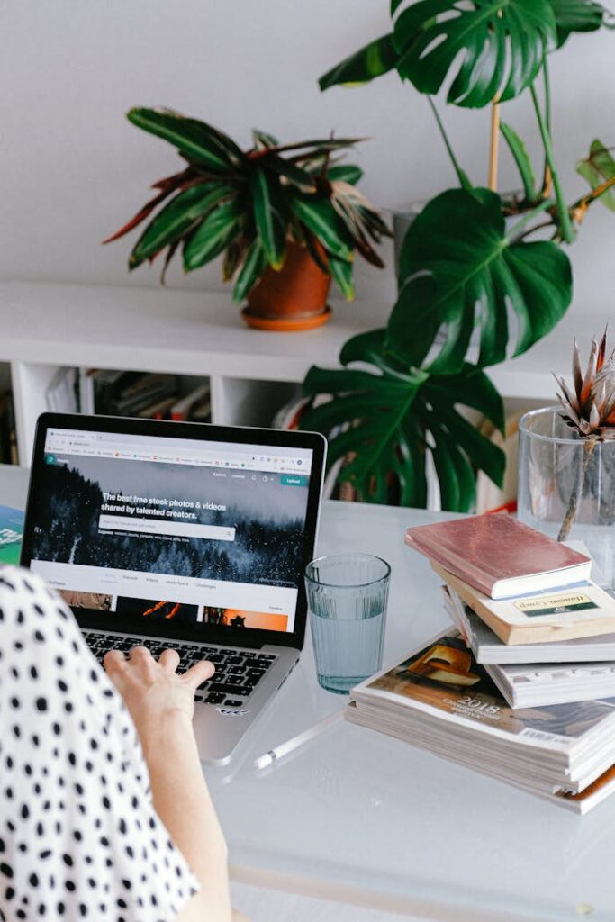 Avasta oma mõtete jõud – 2 nädalat teadlikku fookust A woman working from home on her laptop surrounded by plants and books for a cozy office feel.