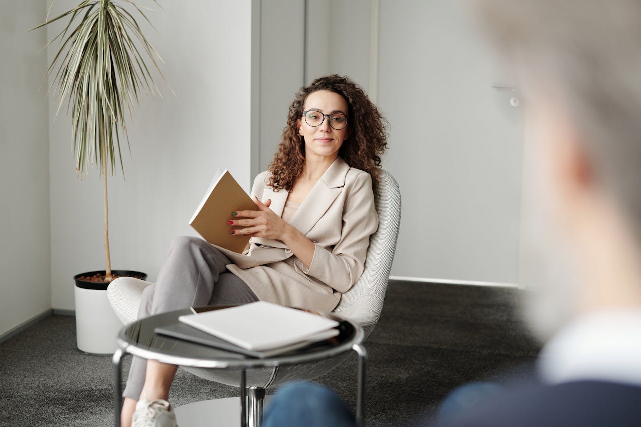 our-story Businesswoman sitting in a modern office with a notebook, exuding professionalism and confidence.